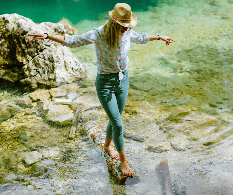Femme équilibrée traversant un ruisseau en montagne